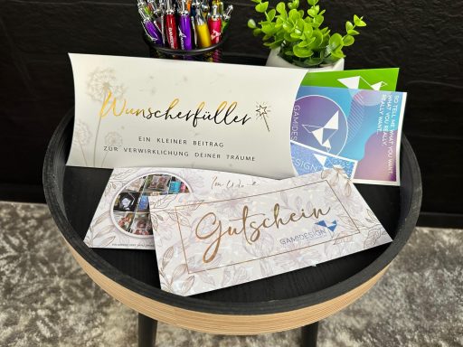 Geschenkgutscheine und Karten auf einem runden Tisch, umgeben von Stiften.