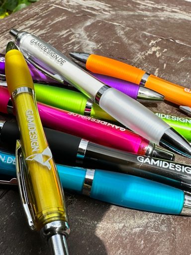 Bunte Kugelschreiber in verschiedenen Farben und Designs auf einem Tisch angeordnet.