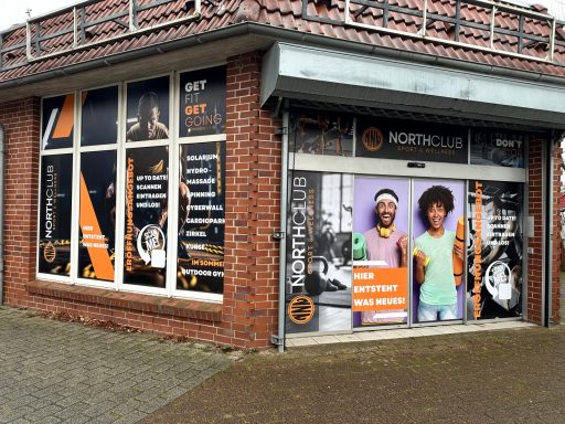 Eingang zu einem Geschäft mit großen Fenstern und bunten, auffälligen Werbeplakaten.