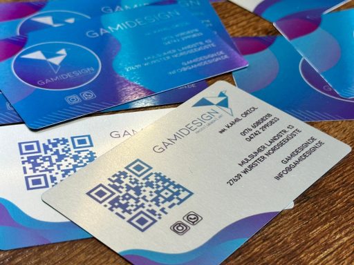 Visitenkarten mit QR-Codes und buntem, modernem Design auf einem Holztisch.