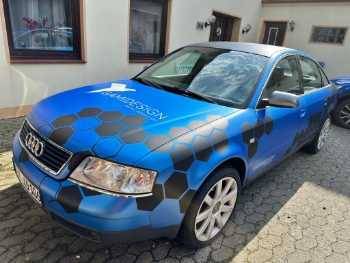 Blauer Audi mit schwarz-rot-gelbem Wabenmuster und grafischem Design.