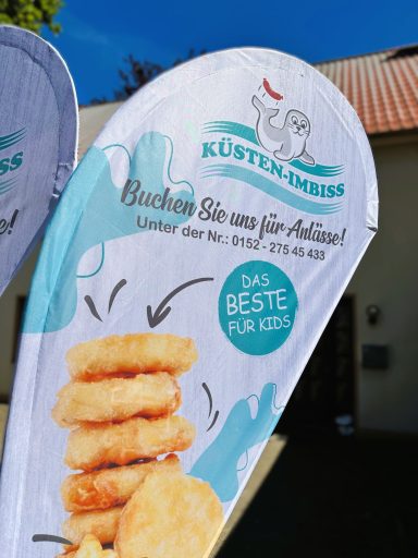 Werbebanner für Küstenfrisch mit einem Hinweis auf Snacks und einem Slogan.
